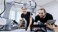 Eine technische Assistentin testet mit einem Techniker in einem Labor den Prototyp eines neuen Roboters.