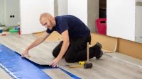 Ein Bodenleger verlegt Vinylboden mit Klickverbindung auf einer Trittschalldämmung.