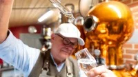 Ein Brenner kontrolliert in seiner Brennerei den von ihm gebrannten Gin.