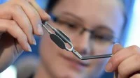Eine Chirurgiemechanikerin des Medizintechnik-Herstellers Aesculap prüft einen Gefäßclip.