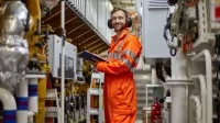 Ein schiffsbetriebstechnischer Assistent steht mit einem Klemmbrett in der Hand im Maschinenraum eines Schiffes.