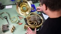 Ein Metallblasinstrumentenmacher baut in seiner Werkstatt ein Horn.