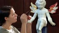 Eine Vergolderin belegt die Flügel einer Engelfigur aus dem 17. Jahrhundert mit 24-karätigem Blattgold. 
