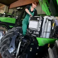 Eine Land- und Baumaschinenmechatronikerin wartet einen Mähdrescher.