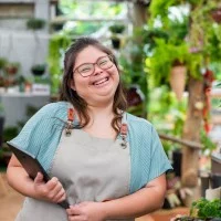 Frau mit Down-Syndrom arbeitet in einem Blumenladen mit Tablet