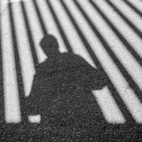 Man sieht den Schatten einer Person hinter dem Schatten von Gitterstäben.