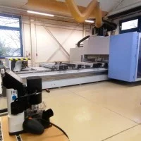 Im Hintergrund eine von drei CNC-5-Achs Maschinen, im Vordergrund eine handgeführte CNC-Maschine.