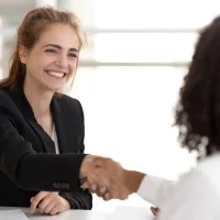 Zwei Frauen geben sich nach einem erfolgreichen Bewerbungsgespräch die Hand.