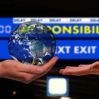 Eine Hand hält einen Erdball vor einer Anzeigetafel