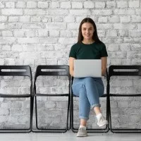 Junge Frau mit Laptop warten auf ihr Bewerbungsgespräch