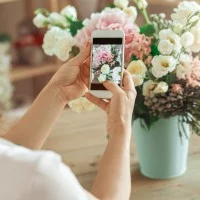 Eine Auszubildende zur Floristin fotografiert einen Blumenstrauß.