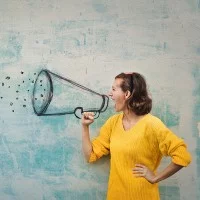 Eine Frau schreit durch ein Megafon, welches als Graffiti an die Wand gemalt ist.