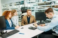 Ein Automobilkaufmann berät eine junge Familie beim Autokauf im Autohaus.