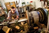 Ein Böttcher arbeitet an einer Ausdrehmaschine in einer Fassfabrik in München.