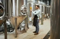 Ein Brauer prüft ein frisch aus der Brauereianlage gezapftes Bier.