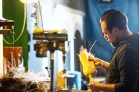 Ein Bürsten- und Pinselmacher fertigt in seiner Werkstatt einen Reisstrohbesen.