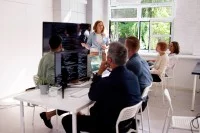 Eine kaufmännische Assistentin / Wirtschaftsassistentin für Betriebsinformatik hält für fünf Personen eine Schulung über das neue Softwareprogramm.