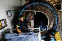 Eine Fachkraft für Lederherstellung und Gerbereitechnik stellt aus Rinderhaut chromgegerbtes, bläuliches Leder für Autositze her.