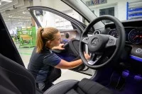 Eine Fahrzeuginterieur-Mechanikerin montiert eine Türinnenverkleidung in eine Autotür.