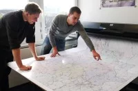 Zwei Geomatiker vom Landesbetrieb Straßenbau Nordrhein-Westfalen überprüfen eine Landkarte, die sie erstellt haben.