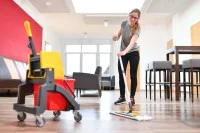 Eine Hauswirtschafterin wischt in einem Freizeitzentrum den Fußboden.