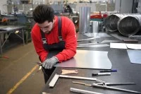 Ein Industrie-Isolierer schneidet einen Blechbogen für eine Isolierung zu.