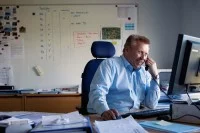 Ein Kaufmann im Eisenbahn- und Straßenverkehr bei DB Schenker organisiert den Warentransport mit Zügen.