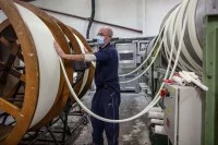 Ein Kerzenhersteller arbeitet an den Trommeln einer Kerzenzuganlage.