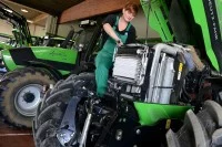 Eine Land- und Baumaschinenmechatronikerin wartet einen Mähdrescher.