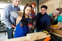 Auzubildende bohrt in ein Brett