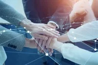 Eine Fotografie von drei Personen, die in der Mitte des Bildes die Hände übereinander legen. Darüber ist ein virtuelles Netz gespannt.