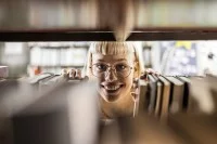 Junge Frau am Bücherregal in einer Bibliothek