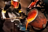 Ein Metall- und Glockengießer gießt den geschmolzenen Stahl in die Werkstückformen.