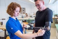 Eine Orthopädietechnik-Mechanikerin passt eine Armprothese an einem Patienten an.