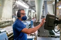 Ein Produktionsmechaniker - Textil bedient eine Textilmaschine.