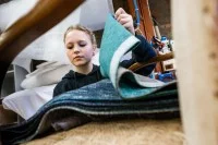 Eine Raumausstatterin wählt aus Stoffen den Bezug für einen Stuhl aus.