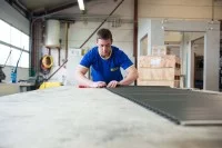 Ein Rollladen- und Sonnenschutzmechatroniker repariert in der Werkstatt einen Rollladen.