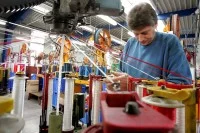 Ein Seiler spannt im Tauwerk Liros Schnüre in eine Maschine.