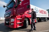 Ein Servicefahrer steigt in seinen Lkw, um saubere Textilien zu einem Kunden zu fahren.