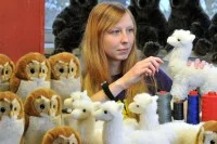 Eine Spielzeugherstellerin kämmt in der Werkstatt die neu hergestellten Alpakas und Eulen aus Plüsch.