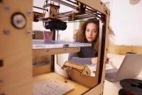 Eine Technische Produktdesignerin überwacht den 3-D-Druck eines Prototyps.
