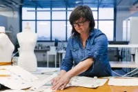 Eine Textil- und Modeschneiderin überträgt vor dem Zuschneiden das Muster auf den Stoff.