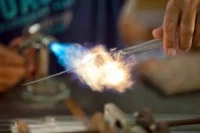 Ein Thermometermacher schmilzt mit einem Brenner einen Sattel an einem Thermometer ein.