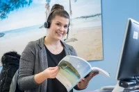 Eine Tourismuskauffrau für Privat- und Geschäftsreisen berät eine Kundin telefonisch.