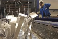 Ein Verfahrensmechaniker entfernt Asche und Restbestände bei der Verzinkung von Stahlteilen im Zinkkessel. 