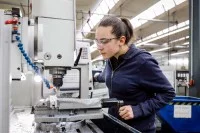 Eine Zerspanungsmechanikerin arbeitet an einer Werkzeugmaschine.