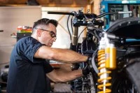 Ein Zweiradmechatroniker repariert in der Werkstatt ein Motorrad.