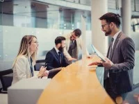 Eine Bankkauffrau berät einen Geschäftskunden am Schalter.