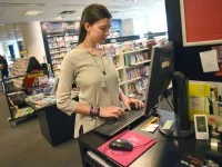 Eine Buchhändlerin prüft im Warensystem den Bestand an Büchern und bestellt fehlende Produkte nach.