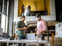 Zwei Assistenten für Medieninformatik testen im Großraumbüro ein AV-Produkt. 